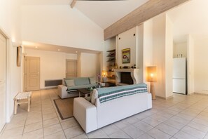 Ein modernes Wohnzimmer mit Sofa, einem kleinen Tisch, einer Bank, einem Kamin und einem Kühlschrank.
