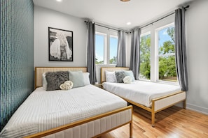 A bedroom with two beds, a window with curtains, a wall-mounted picture, and a patterned curtain on the left. - 6 Min to DT! Luxe Home! Karaoke Stage! (Nashville)