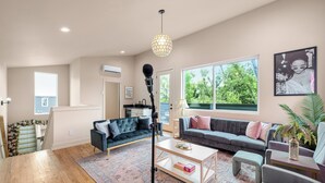 Ein geräumiges Wohnzimmer mit großem Fenster, einer Couch, einem Couchtisch und einem Mikrofonständer.