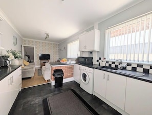 A modern kitchen with a washing machine, a microwave, and a sink.