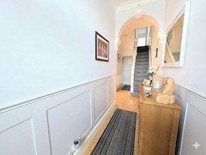 A hallway with a wooden cabinet, a framed picture, and a staircase.