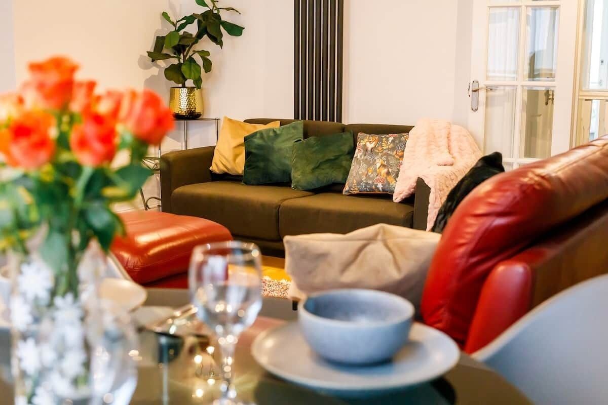 A living room with a sofa, cushions, a table with a bowl and wine glass, and a plant.