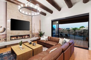Ein modernes Wohnzimmer mit Kamin, Ledersofa, Couchtisch aus Holz und einem großen Fernseher.
