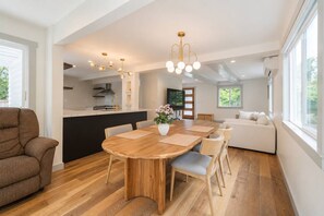 Ein modernes Interieur mit einem Holzesstisch, einer Couch und einer Küchenzeile.