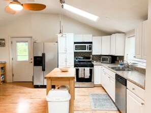 A kitchen with white cabinets, a microwave, stove, and a sink. - Owasco Lake Cottage | Lake Front | Dock | Fire Pit (Moravia)