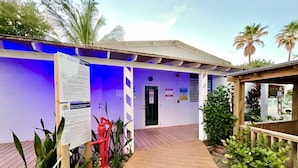 A building with a wooden deck, a door, and informational signs. - Apto 2A Flamenco Beachfront Villas with Ocean View (Flamenco)
