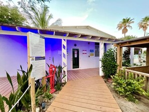 Un bâtiment doté d’une terrasse en bois, d’une porte et de panneaux d’information.