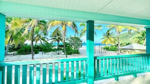 A covered outdoor area with a turquoise railing, palm trees, and a beach view. - Apto 2A Flamenco Beachfront Villas with Ocean View (Flamenco)