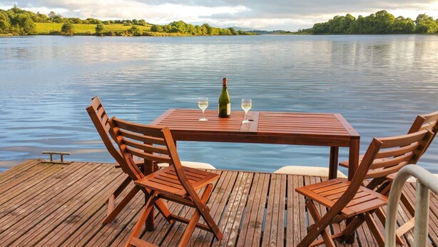 Eine Holzterrasse mit Tisch und Stühlen mit Blick auf einen ruhigen See.
