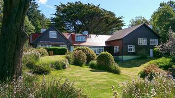 A large house with a well-maintained lawn, surrounded by trees and shrubs.