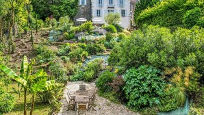 A lush garden with a variety of plants and a rustic wooden table. - Le Jardin Du Chateau (Duras)
