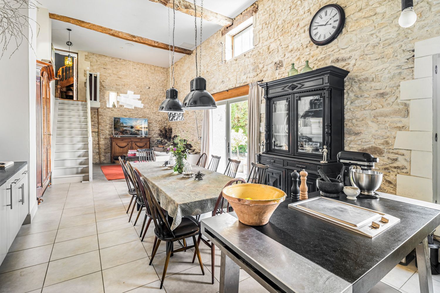 A modern kitchen with a stone wall, a large island, and a dining area.