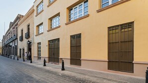 Een straat met gebouwen, een verharde weg en paaltjes.