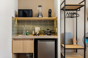 Una cocina compacta con microondas, licuadora, fregadero y un refrigerador pequeño.