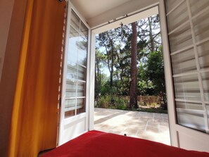 An open sliding glass door leading to a patio with a stone floor and a wooden fence.