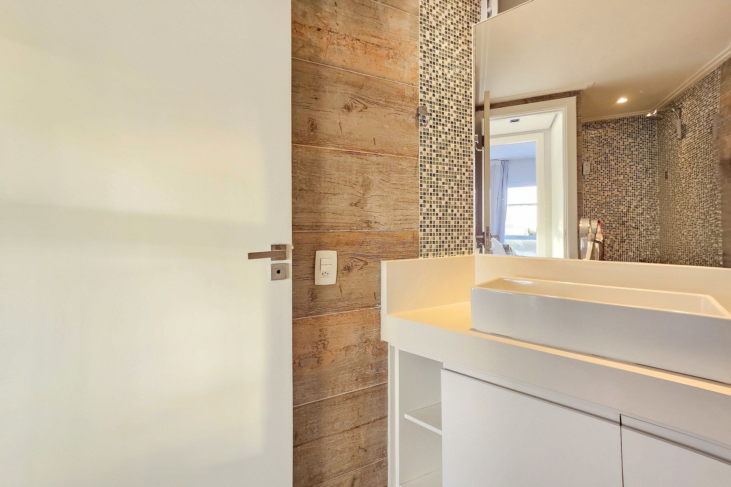 A modern bathroom with a wooden wall, a white sink, and a mirror.