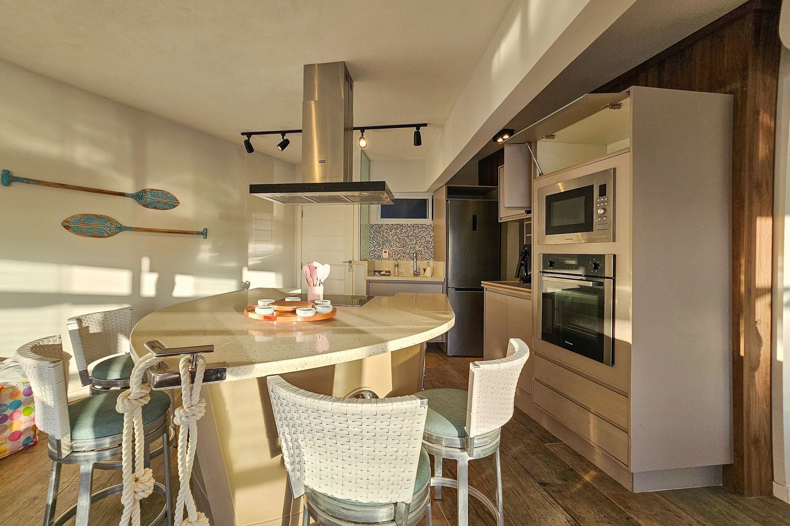 Cocina moderna con una isla central, electrodomésticos de acero inoxidable y un techo alto.
