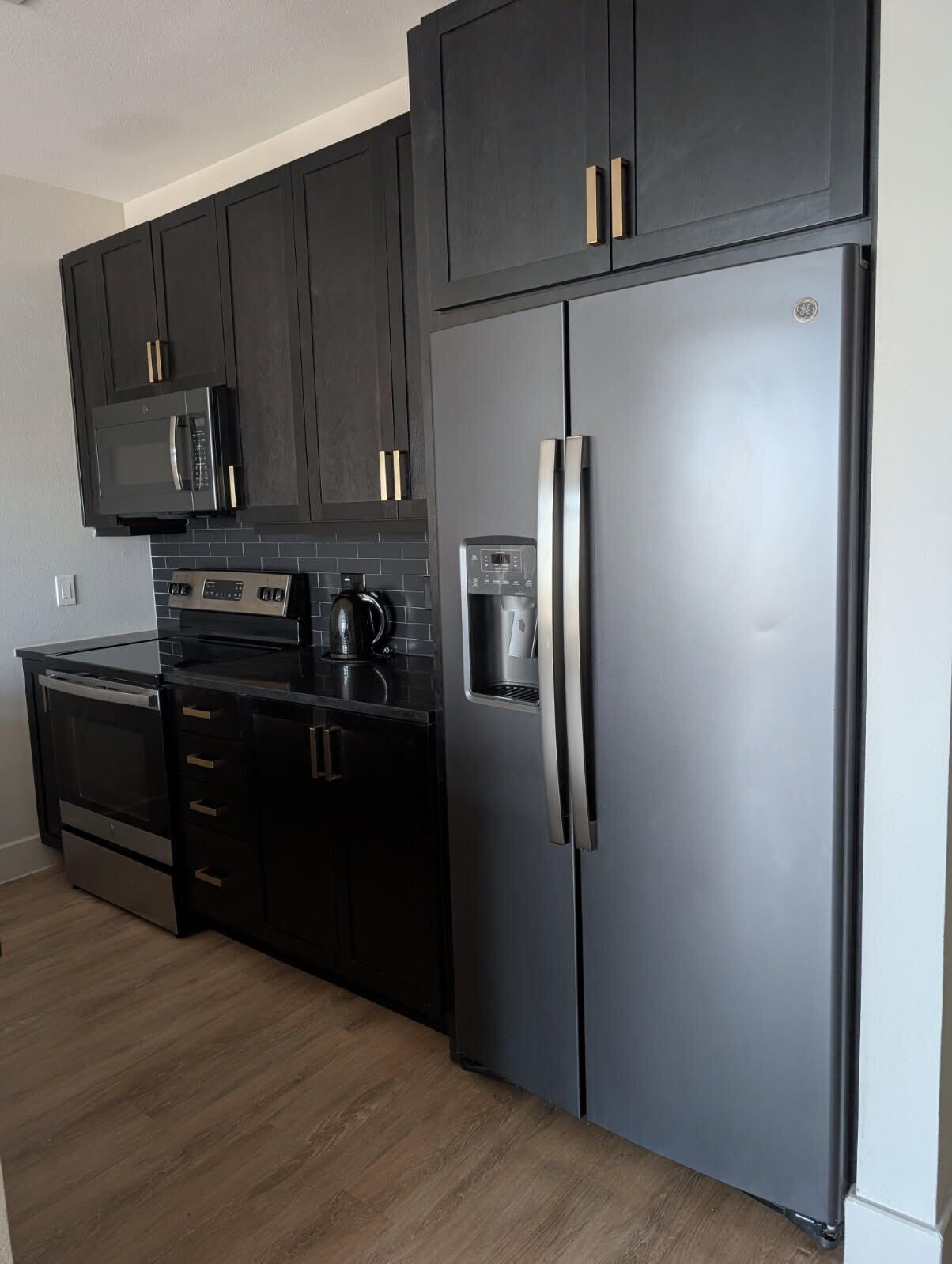A modern kitchen with dark cabinetry, stainless steel appliances, and a built-in oven.