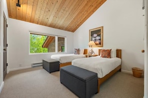 Un dormitorio con dos camas, una ventana, techo de madera y un cuadro.