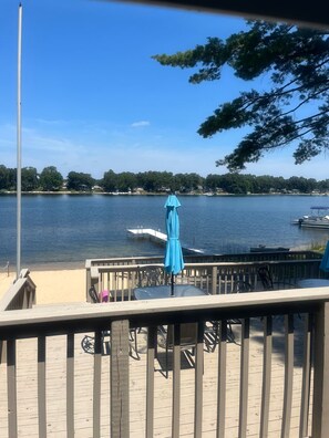Eine Holzterrasse mit Tisch und Stühlen, mit Blick auf einen See mit Booten und einem Steg.