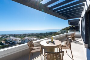 A balcony with a round table, chairs, and a bottle of olive oil. - Bali II | Costa del Sol Penthouse with Amazing Views (Rincón de la Victoria)