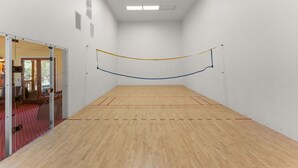 A squash court with a wooden floor, a net, and a door leading to an outdoor area. - Private Lake - 19 Acres - Fishing, Game Room, Pool/Spa, Amenities Galore! (Fallbrook)