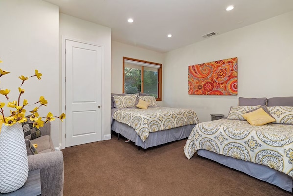 Un dormitorio con dos camas, una ventana, una puerta y un cuadro en la pared.