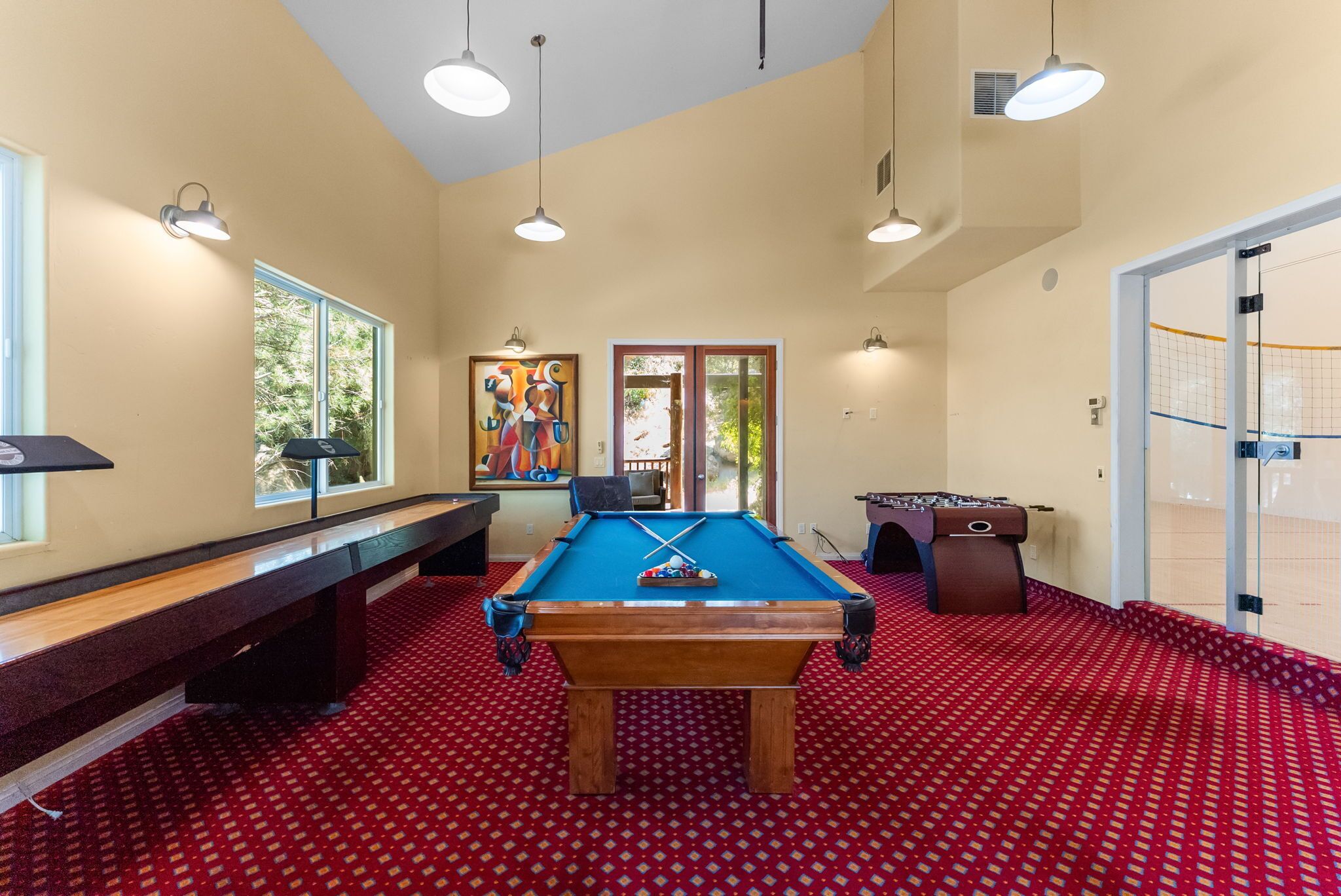 A pool table with a blue felt surface, a billiards rack, and a cue stick.