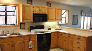 A kitchen with wooden cabinets, a microwave, stove, and a sink.