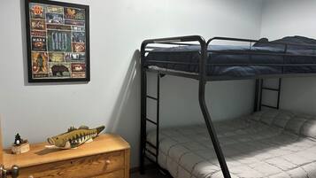 A bunk bed room with a framed poster on the wall, a wooden dresser, and a small fish figurine.