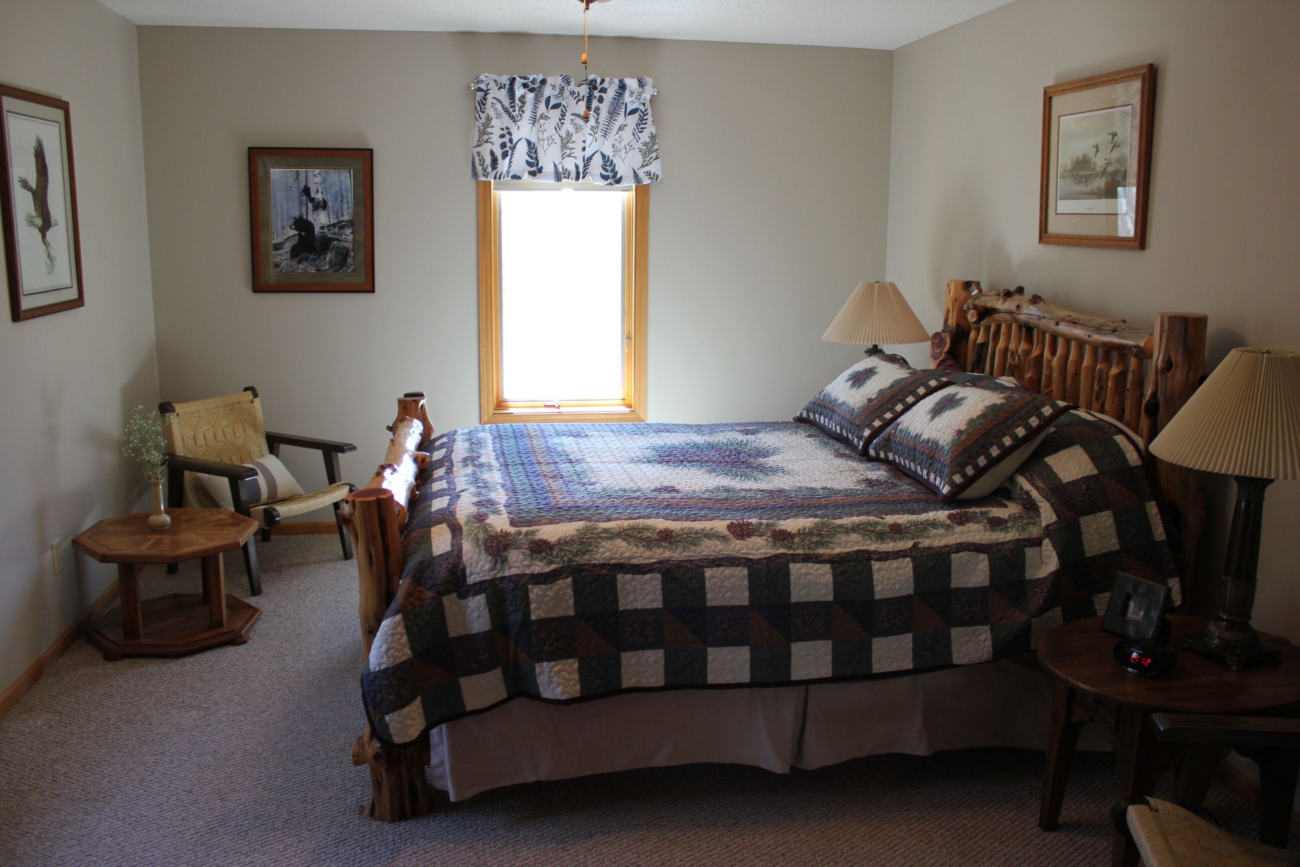 A bedroom with a large bed, a chair, a table, and a window with a view.