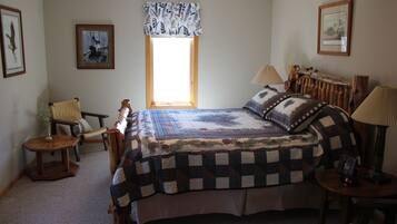 A bedroom with a large bed, a chair, a table, and a window with a view.