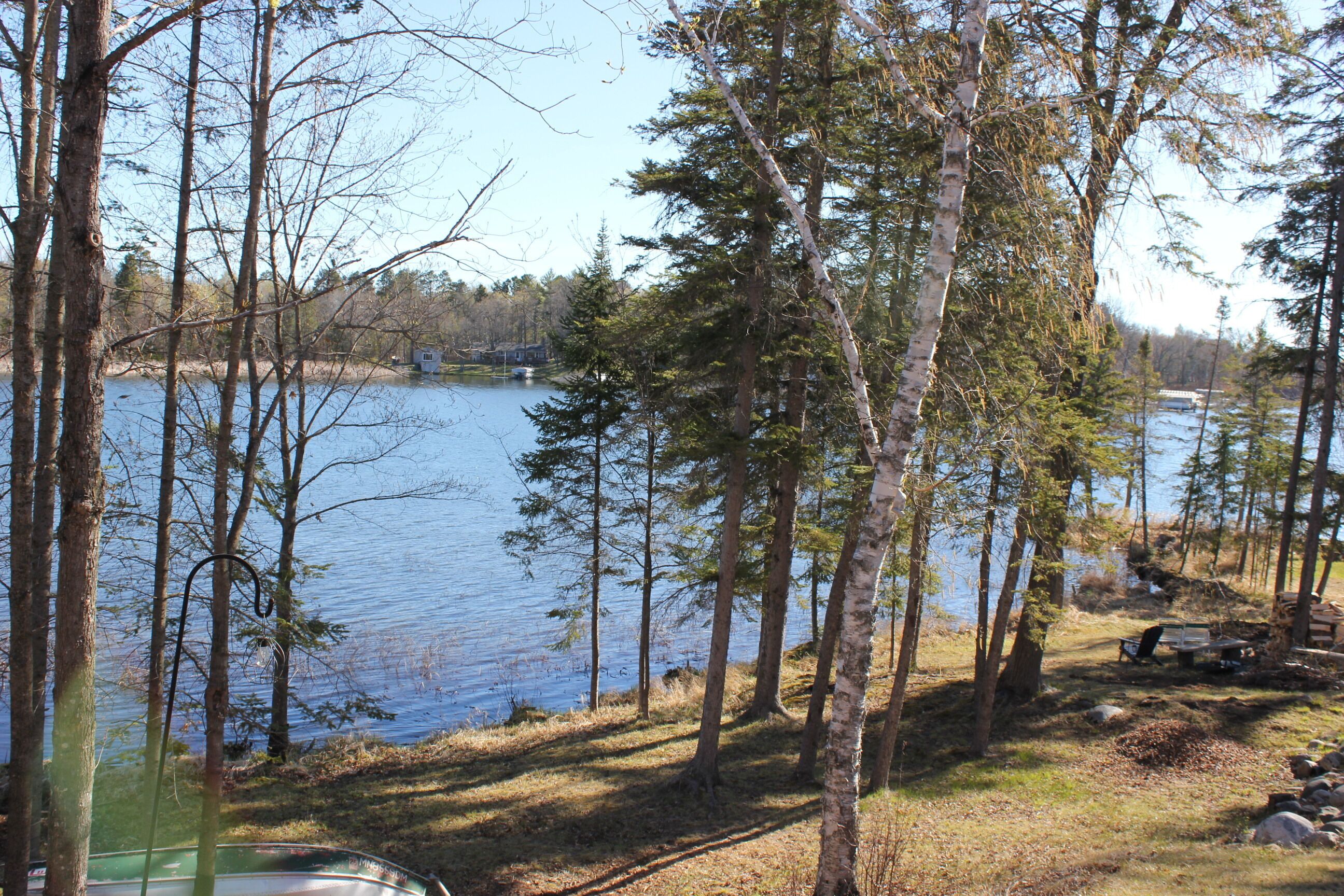 A lakeside cabin with a dock, surrounded by trees and a clear view of the lake.