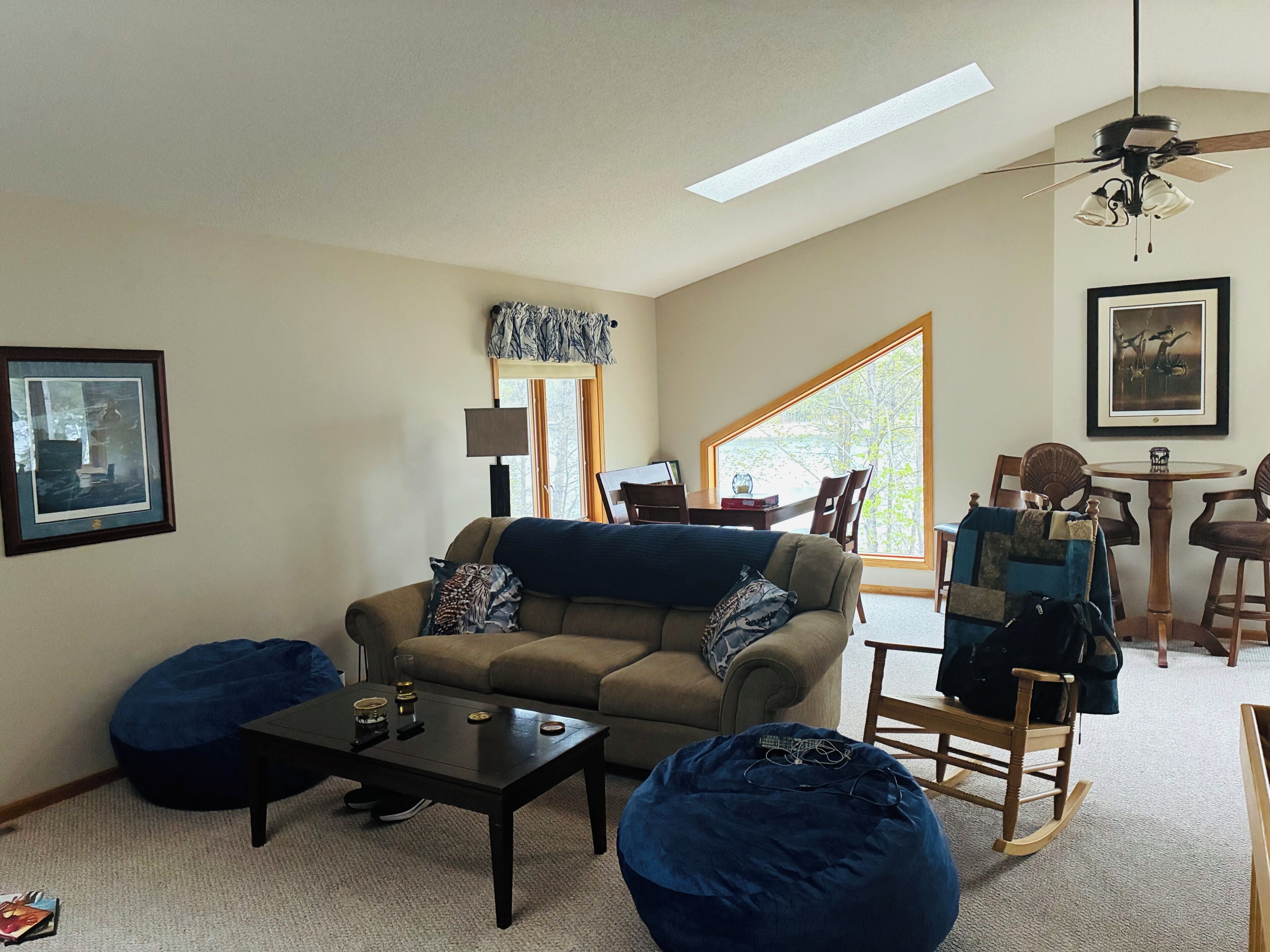 A living room with a sofa, coffee table, bean bag, and a ceiling fan.