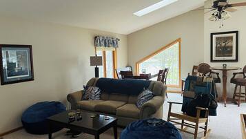 A living room with a sofa, coffee table, bean bag, and a ceiling fan.