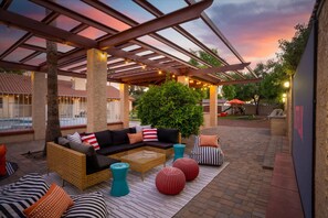Eine Terrasse im Freien mit überdachter Sitzgelegenheit, einem Pool und einem angelegten Garten.