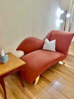 A modern living room with a red sofa, a wooden coffee table, and a white pillow. - Stylish 2BR + Office | Near Cleveland Clinic+Shops (South Euclid)