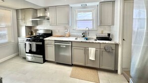A modern kitchen with stainless steel appliances, a central island, and a ceiling light fixture. - Stylish 2BR + Office | Near Cleveland Clinic+Shops (South Euclid)