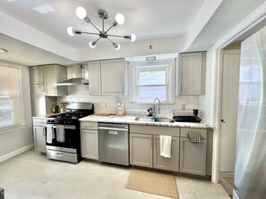 A modern kitchen with stainless steel appliances, a central island, and a ceiling light fixture. - Stylish 2BR + Office | Near Cleveland Clinic+Shops (South Euclid)
