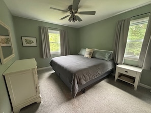 A bedroom with a bed, a nightstand, a dresser, a ceiling fan, and two windows with curtains. - Home near the Indiana Dunes National & State Parks! (Michigan City)