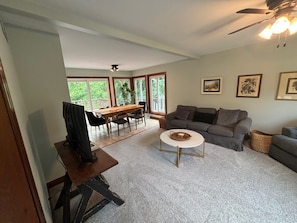 A spacious living area with a dining table, sofa, and a ceiling fan.