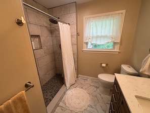 A bathroom with a shower, toilet, and sink.