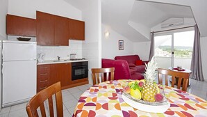 Een moderne keuken met houten kastjes, een eettafel met een kleurrijke tafelkleed en een schaal fruit.
