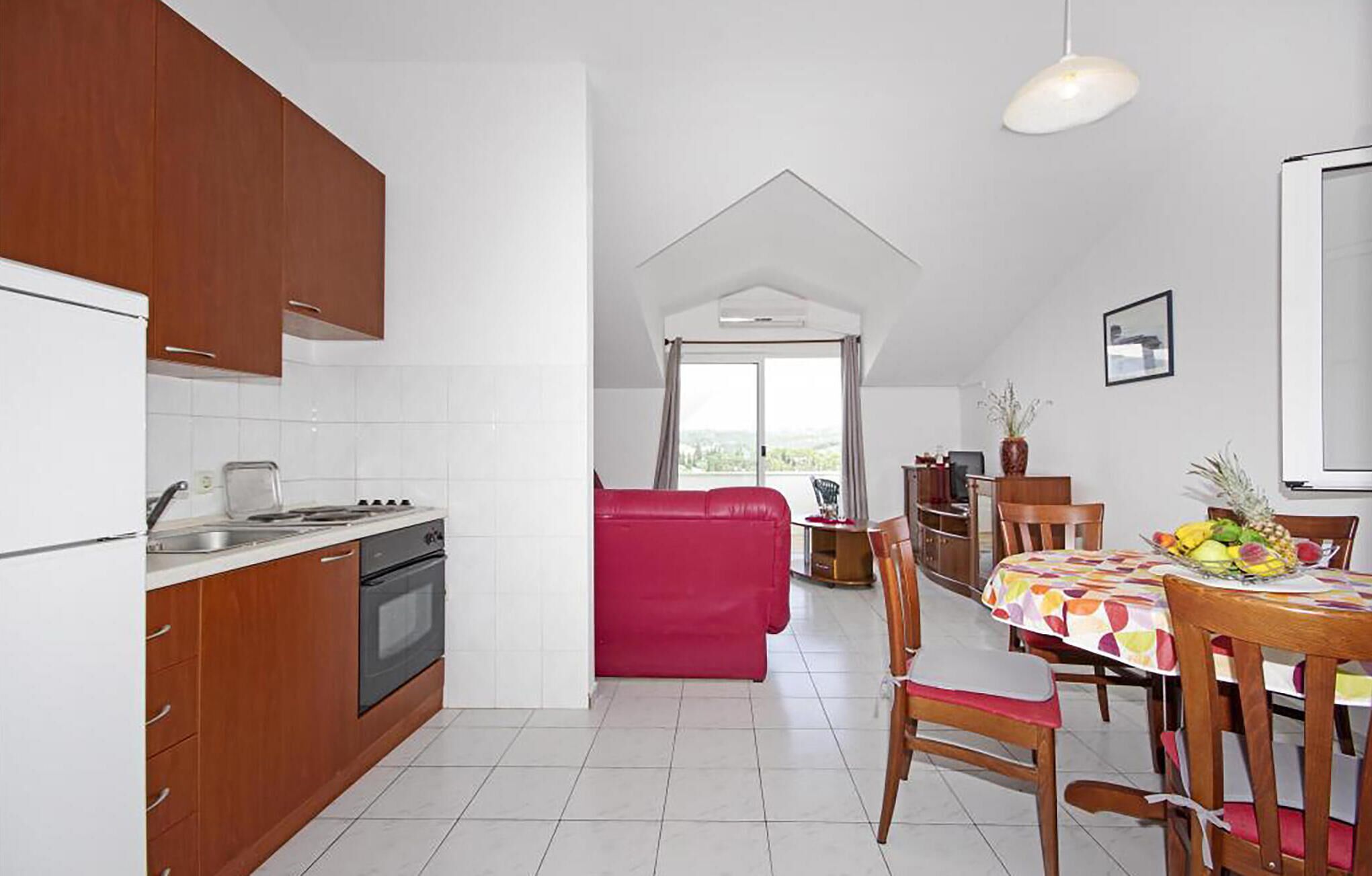 Une cuisine compacte avec un coin repas, un canapé rouge et une table mise pour le dîner.