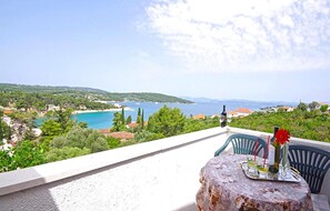 Ein Balkon mit Tisch, Stühlen und Blick auf eine Küstenlandschaft.