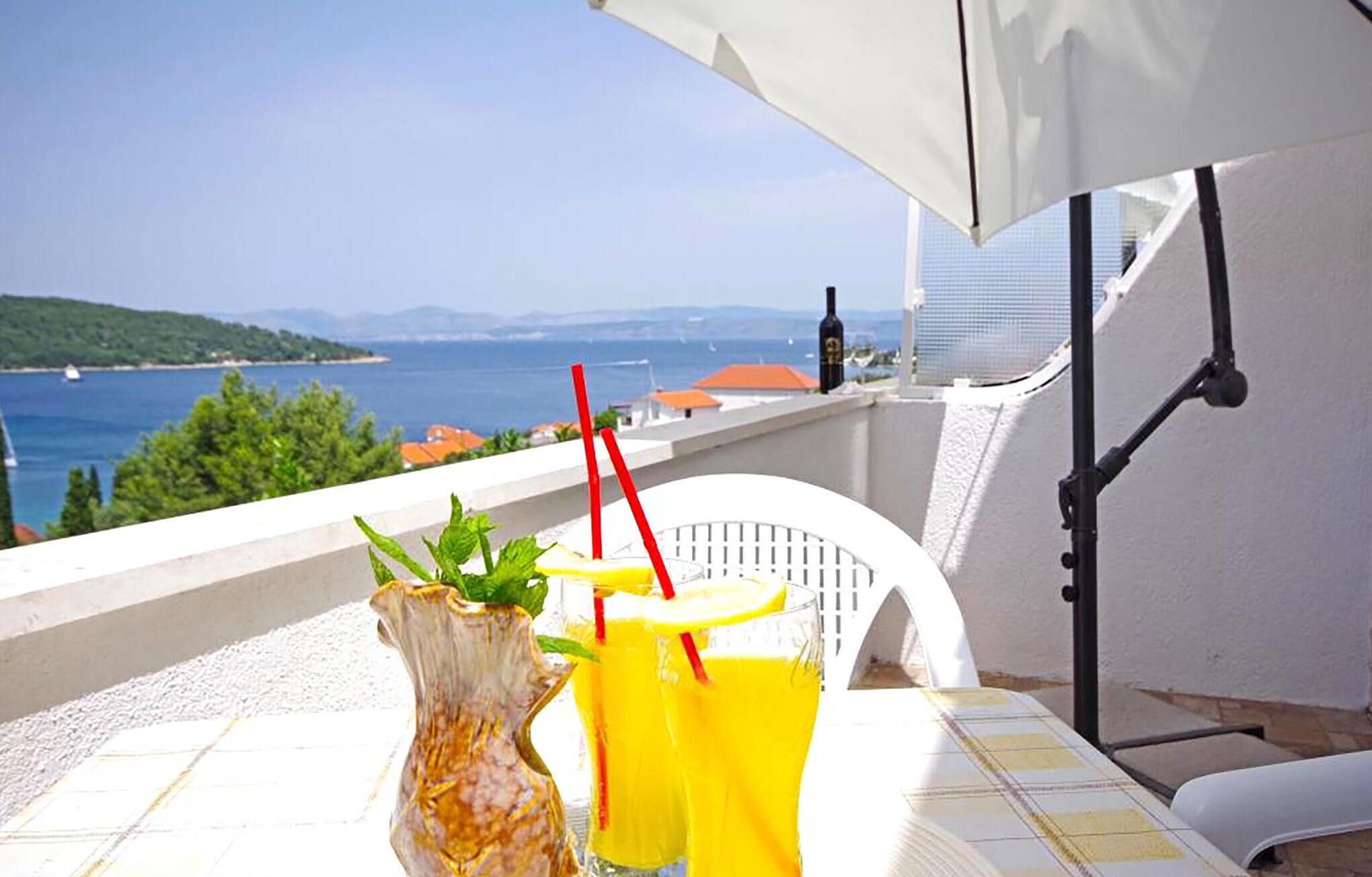 Ein Balkon mit Tisch, einer Vase und zwei Getränken.