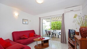 A living room with a red sofa, a coffee table, a TV, and a sliding glass door leading to an outdoor area. - Gorgeous apartment in Necujam with WiFi (Necujam)