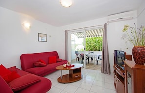 A living room with a red sofa, a coffee table, a TV, and a sliding glass door leading to an outdoor area. - Gorgeous apartment in Necujam with WiFi (Necujam)