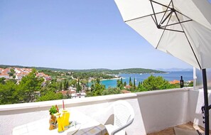 A balcony with a white umbrella, a table with drinks, and a view of a coastal town and sea. - Beautiful apartment in Necujam with WiFi (Necujam)