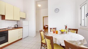 A compact kitchen with white cabinets, a dining table with chairs, and a clock on the wall. - Beautiful apartment in Necujam with WiFi (Necujam)